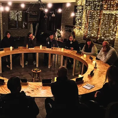 De ronde raadstafel vol kaarsen, met kerstverlichting op de achtergrond